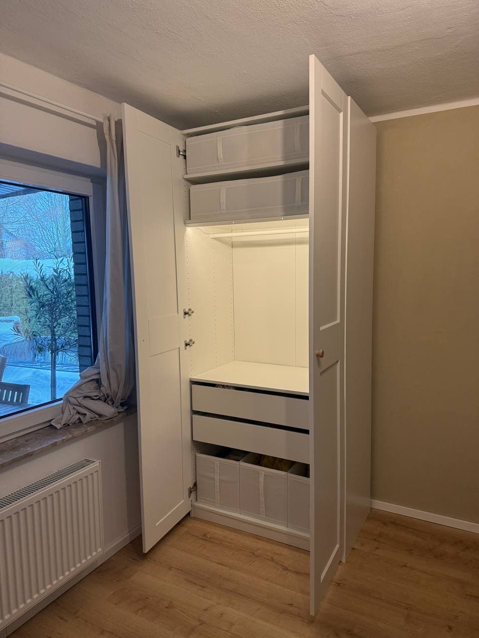 Weißer Kleiderschrank mit geöffneten Türen: Innenschubladen, Aufbewahrungsboxen und Innenbeleuchtung